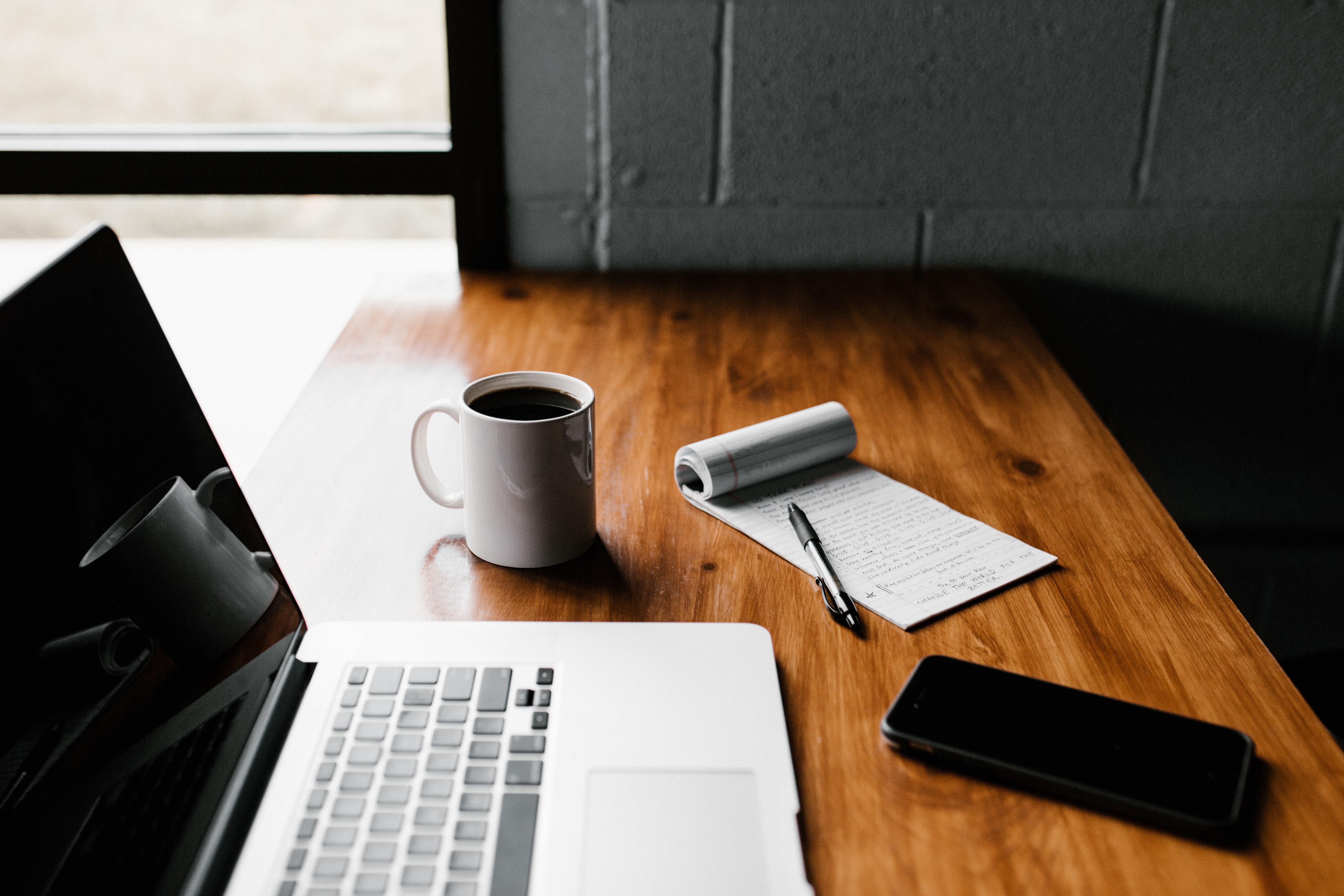 A desk with a laptop, a smartphone and a coffee cup